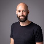 Das lvh-Team Porträt eines lächelnden Mannes mit Bart und schwarzem T-Shirt vor grauem Hintergrund