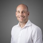 Weiterbildung Porträt eines lächelnden Mannes mit weißem Hemd vor grauem Hintergrund