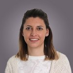 Das lvh-Team Porträt einer lächelnden Frau mit mittellangen braunen Haaren vor grauem Hintergrund