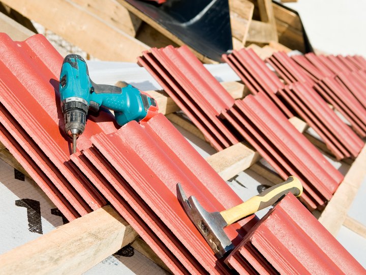 Dachdecker Blaue Bohrmaschine und Hammer auf roten Dachziegeln beim Dachbau