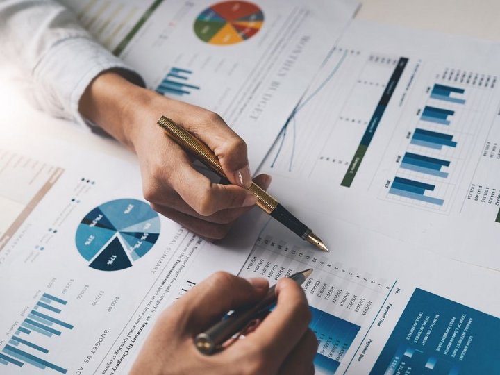 Steuerberatung, Buchhaltung und Lohnabrechnung Person analysiert Finanzberichte mit Diagrammen und Tabellen