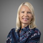 Orthopädieschuhmacher Porträt einer lächelnden blonden Frau vor grauem Hintergrund