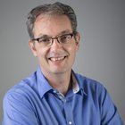 Sägewerker und Verpackungshersteller Porträt eines lächelnden Mannes mit Brille und blauem Hemd vor grauem Hintergrund