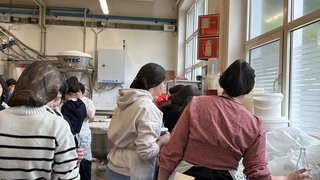 Junghandwerker Menschen mit Haarnetzen und Schürzen in einer industriellen Küche oder Produktionsstätte.