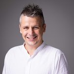 Das lvh-Team Lächelnder Mann mit weißem Hemd vor grauem Hintergrund