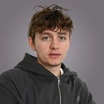 Das lvh-Team Junger Mann mit zerzausten braunen Haaren und schwarzer Kapuzenjacke vor grauem Hintergrund