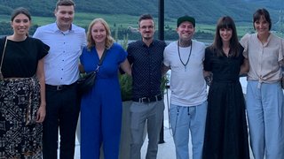 Junghandwerker Sieben Personen stehen Arm in Arm vor einer Berglandschaft