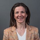 Textil und Leder Porträt einer lächelnden Frau mit braunen Haaren vor grauem Hintergrund