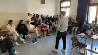 Junghandwerker Junger Mann hält Vortrag vor einer Gruppe von Jugendlichen in einem Klassenraum