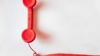 Nachhaltiges Handwerk Roter Telefonhörer mit gewickeltem Kabel auf weißem Hintergrund