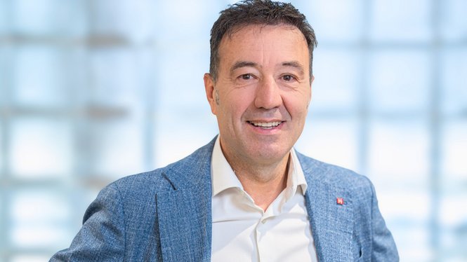 Home Porträt eines lächelnden Mannes mit blauem Sakko vor hellem Hintergrund