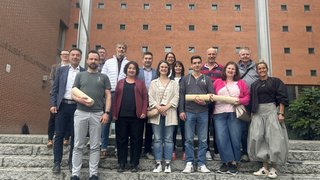 News Gruppo di 15 persone su scale davanti a edificio rosso