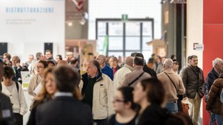 News Molte persone camminano in un affollato padiglione fieristico