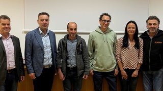 News Sei persone in piedi in fila davanti a una parete in un ambiente interno