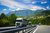 Home LKWs fahren auf Autobahn vor Berglandschaft unter blauem Himmel mit Wolken