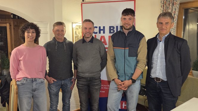 Home Fünf Personen stehen vor Banner in Zimmer bei Veranstaltung