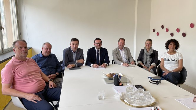 Home Sieben Erwachsene sitzen an einem weißen Tisch in einem Büro mit Fenstern