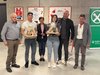 Home Sechs Personen posieren mit Geschenken vor Sporttrikots und Raiffeisen-Banner