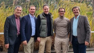 News Fünf lächelnde Männer stehen vor Gräsern im Freien