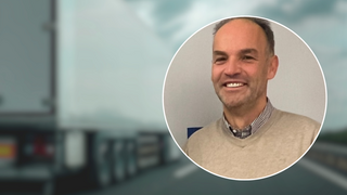 News Uomo sorridente davanti a un camion sfocato sulla strada