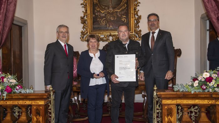 Südtiroler Wirtschaftspreis: Viel Ehre für das Handwerk Vier Personen posieren mit einer Urkunde in einem festlichen Raum mit Blumen