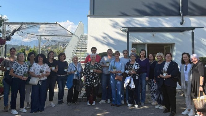Home Eine Gruppe von Frauen und einem Mann steht vor einem Gebäude und einem Gewächshaus