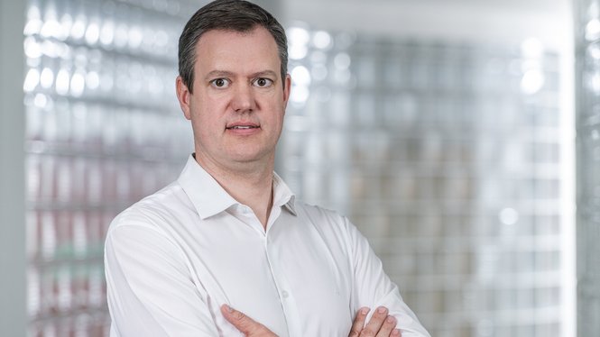 Home Mann im weißen Hemd steht mit verschränkten Armen vor hellem Hintergrund