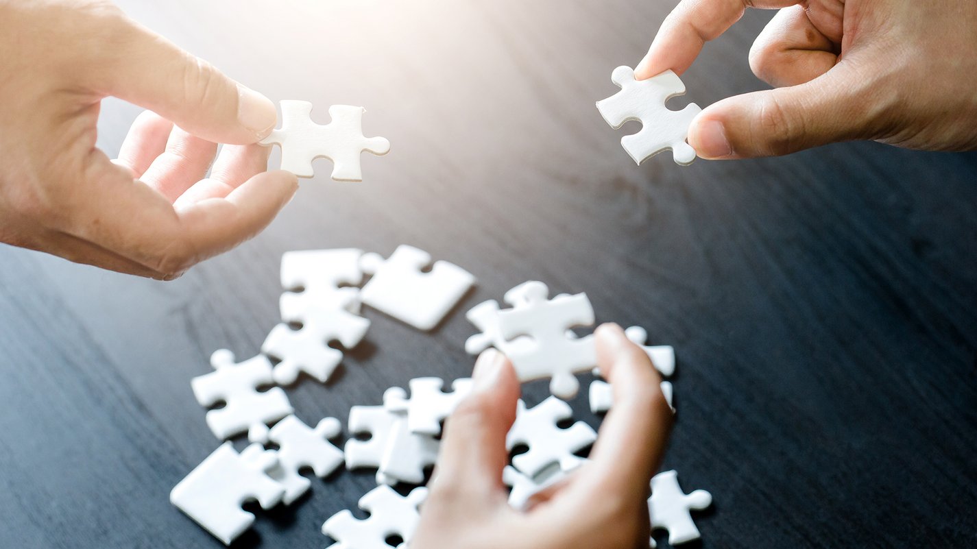 Home Hände halten weiße Puzzleteile über einem Tisch