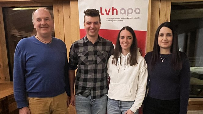 Home Vier Personen stehen vor einem lvhapa-Banner in einem Holzraum