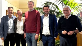 News Fünf Personen in einem Innenraum vor Pflanzen posierend, lächelnd.