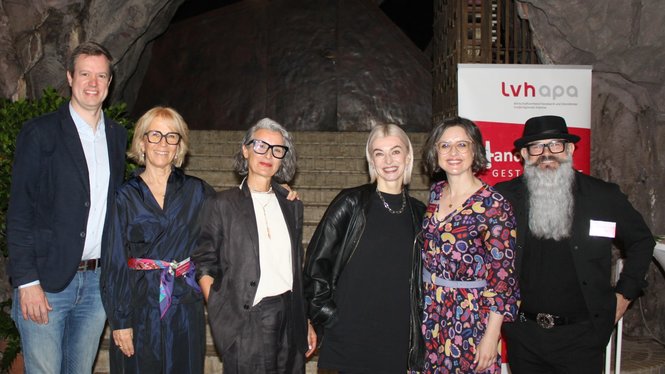 Home Gruppenfoto von sechs Personen vor einem Felsbogen und einem LVH-Apa Banner