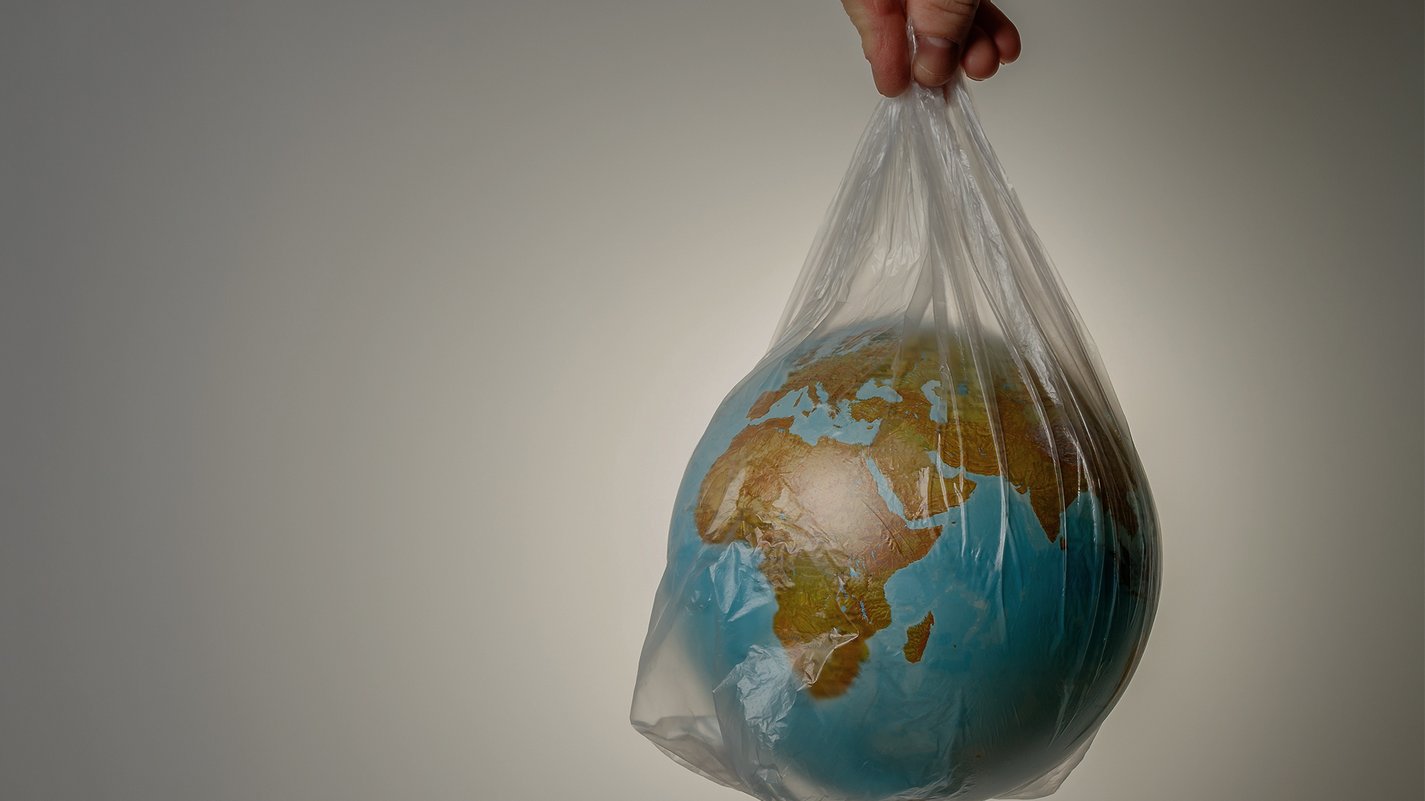 Home Erde in einer Plastiktüte gehalten, symbolisch für Umweltschutz