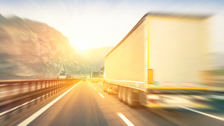News Camion in velocità su autostrada con paesaggio montano al tramonto