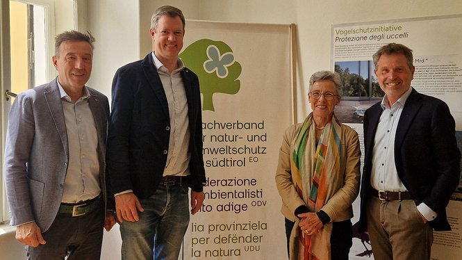 Home Vier Personen stehen vor Bannern der Umweltschutzorganisation Cipra Südtirol