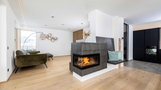 News Moderner Wohnraum mit Kamin, grünem Sofa und Holzboden