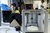 Home Frau mit Schutzbrille arbeitet neben einem Ultimaker-3D-Drucker, im Hintergrund ein Mann