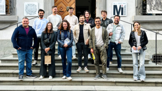 News Gruppo di 13 persone sulle scale davanti a edificio storico