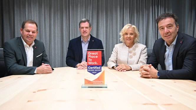 Home Vier Personen sitzen hinter einem Tisch mit einem Great Place to Work-Zertifikat