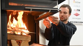 News Uomo accende pezzi di legno in una stufa