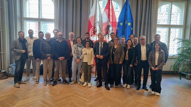 Home Gruppenfoto von Menschen vor Österreich- und EU-Flaggen in einem Saal