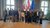 Home Gruppenfoto von Menschen vor Österreich- und EU-Flaggen in einem Saal