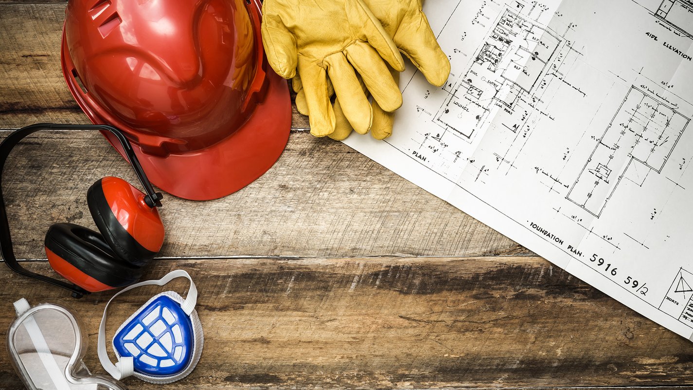 Home Bauhelmm, Handschuhe, Gehörschutz, Atemschutzmaske, Schutzbrille und Bauplan auf Holztisch