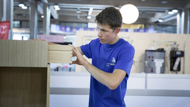 Home Junger Mann arbeitet an einem Holzschrank in einer Werkstatt