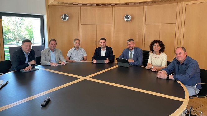Home Sieben Personen sitzen um einen großen Konferenztisch in einem Büro