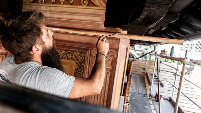 Home Mann mit Bart malt filigrane Muster an eine Wand mit Pinsel