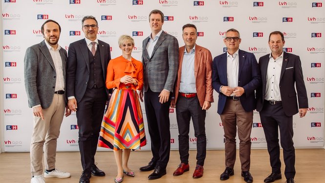 Home Sieben Personen posieren vor lvh apa Werbewand, formell gekleidet