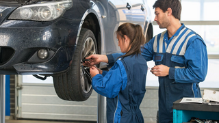 News Due meccanici in officina montano una ruota su un'auto sollevata