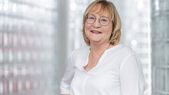 Home Porträt einer lächelnden älteren Frau mit Brille vor hellem Hintergrund