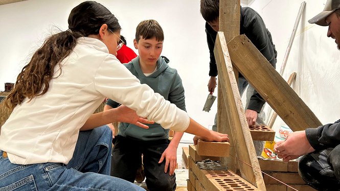 Home Jugendliche lernen gemeinsam das Mauern mit Ziegelsteinen und Mörtel
