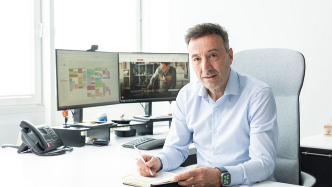 Home Mann schreibt in einem Büro an seinem Schreibtisch mit zwei Monitoren